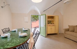 Ein Essbereich mit einem grünen Marmortisch, Stühlen und einem Schrank mit Geschirr.