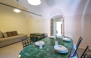 Ein Essbereich mit einem grünen Marmortisch, Stühlen und Tellern.