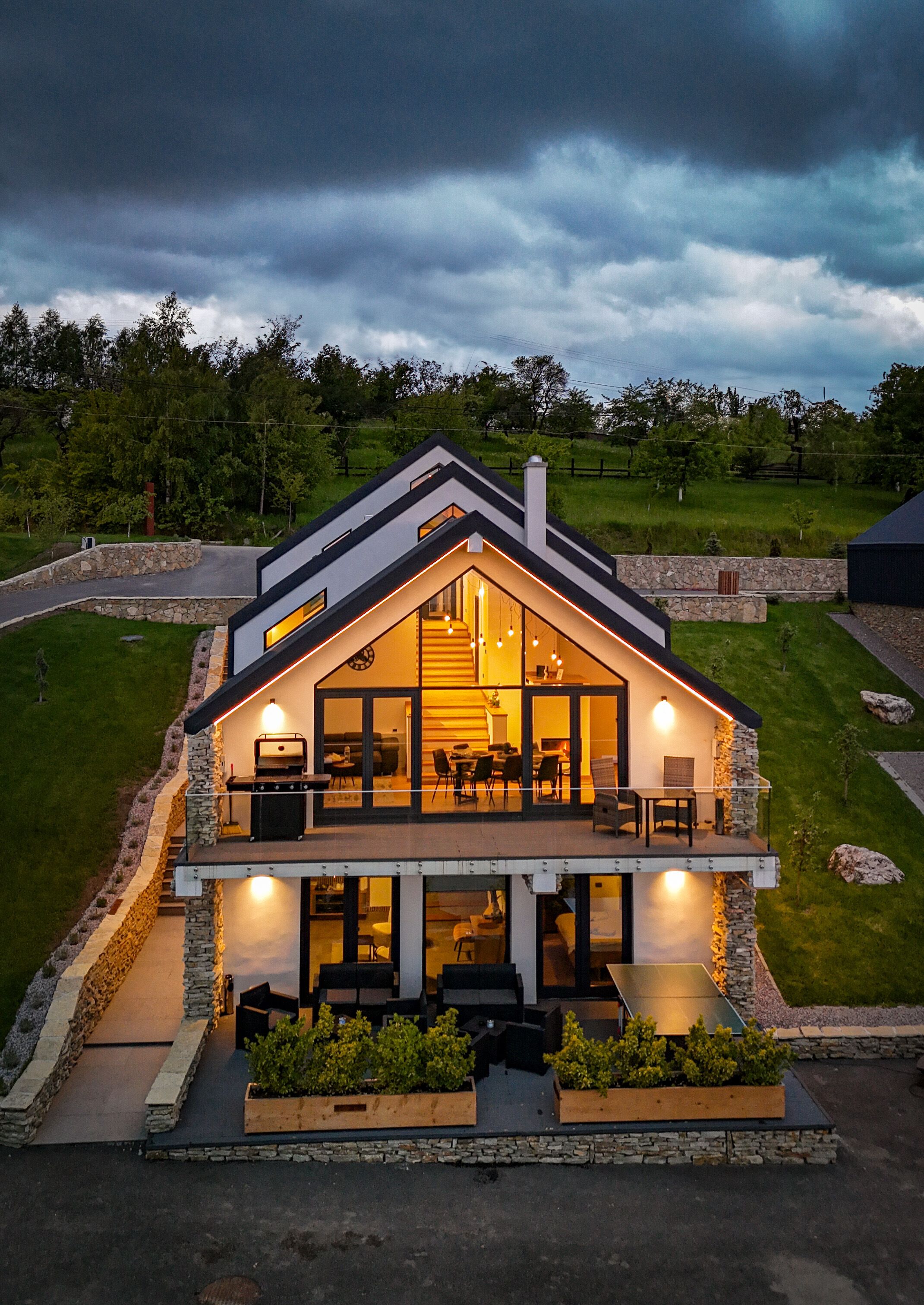 Een modern huis met een groot balkon, stenen muren en een goed verlicht interieur.