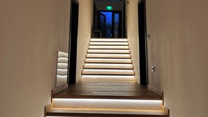 A staircase with illuminated steps leading to a second-floor landing.