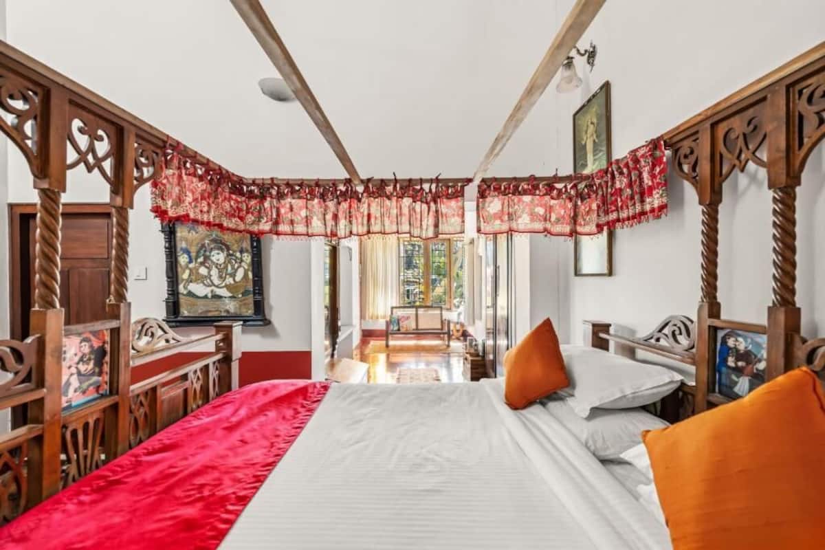 A bedroom with a bed, wooden headboard, and a red curtain.