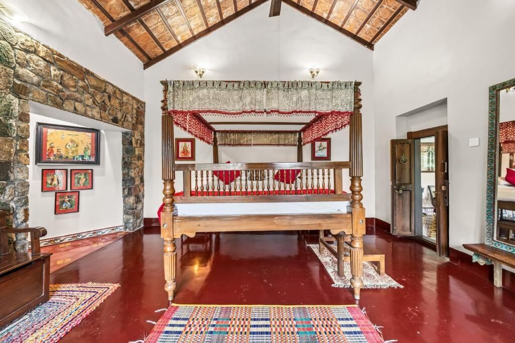 A room with a four-poster bed, stone wall, and artwork on the wall.