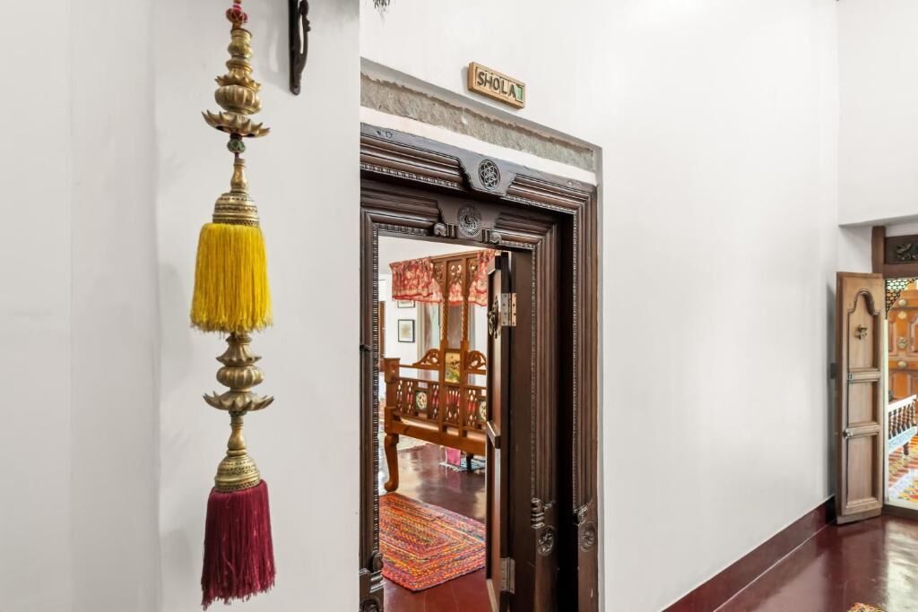 A doorway with a sign reading 'SHOLAT,' a hanging decorative object, and a glimpse of a traditional wooden chair inside.