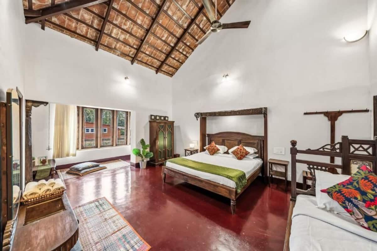 A spacious room with a large bed, wooden furniture, and a high ceiling.