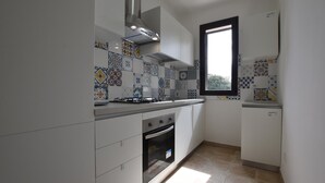 A kitchen with a gas stove, oven, and tiled backsplash. - Cozy home in Caltagirone with WiFi (Caltagirone)