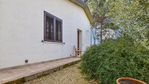 A white building with a window and a door, a small outdoor seating area with two chairs, and a potted plant. - Cozy home in Caltagirone with WiFi (Caltagirone)