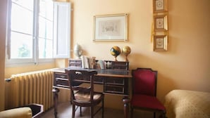 A room with a desk, two chairs, a radiator, a window, and framed pictures on the wall. - Casale novilara (Novilara)