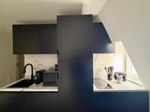 Ett modernt kök med mörka skåp, en inbyggd spis och ett fönster som släpper in naturligt ljus.