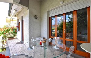 A glass table with white cups and saucers, a wooden door with glass panels, and a view of a garden with red flowers. - 2 bedroom stunning home in Lido di Camaiore (Lido di Camaiore)