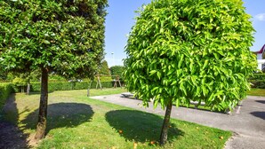 A well-maintained garden with mature trees, a paved walkway, and a clear sky. - 2 bedroom stunning home in Lido di Camaiore (Lido di Camaiore)