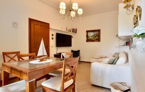 A living room with a wooden dining table, chairs, a sofa, a TV, and a chandelier. - 2 bedroom stunning home in Lido di Camaiore (Lido di Camaiore)