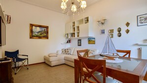 A dining area with a glass table, wooden chairs, a white sofa, and a bookshelf. - 2 bedroom stunning home in Lido di Camaiore (Lido di Camaiore)