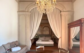 Ein Schlafzimmer mit einem großen Bett, einer Couch, einer Kandelaber und einem Spiegel.
