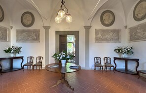 Ein Esszimmer mit einem runden Tisch, Stühlen und zwei Beistelltischen mit Blumenvasen.
