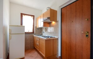 A compact kitchen with a refrigerator, stove, wooden cabinets, and a window. - 3 bedroom stunning apartment in Pomonte (Pomonte)