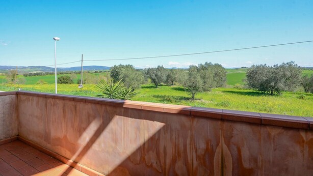 Un balcon donnant sur des champs verdoyants et des arbres.