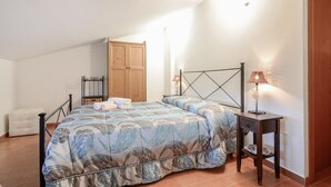 Une chambre à coucher comprenant un lit, deux tables de chevet, une armoire en bois et une chaise.