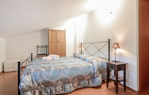 A bedroom with a bed, two bedside tables, a wooden wardrobe, and a chair. - 3 bedroom stunning apartment in Pomonte (Pomonte)