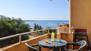A balcony with a table, chairs, a bottle, and a glass. - Beautiful apartment in Marina di Modica with WiFi (Marina di Modica)