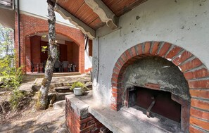 Ein Backofen aus Ziegeln, eine Sitzgelegenheit im Freien und ein Baum in einem Innenhof.