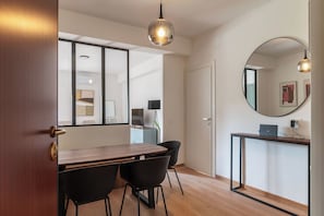 A modern kitchen with a wooden table, black chairs, and a round mirror on the wall. - Stylish Balcony Flats by the Vatican (Roma)
