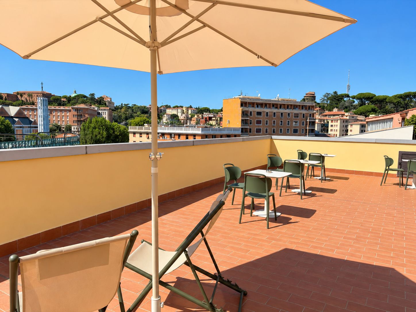 A rooftop terrace with outdoor seating, a large umbrella, and a view of the cityscape.