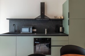 A compact kitchen with a microwave, kettle, and oven. - Stylish Balcony Flats by the Vatican (Roma)
