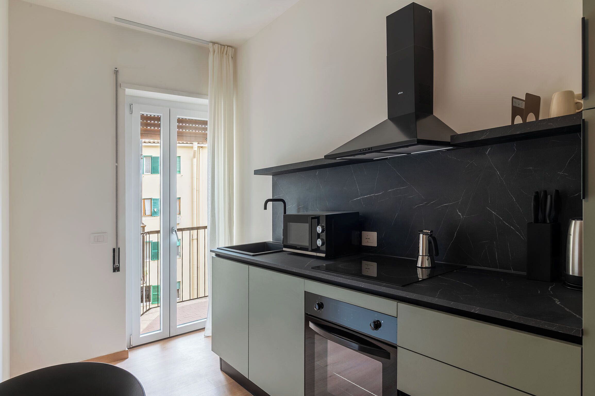 Una cucina moderna con un piano di lavoro nero, un forno a microonde integrato, una macchina da caffè e una lavastoviglie.