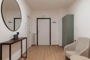 A hallway with a wooden floor, a round mirror, a desk with a laptop, a door, and a green cabinet. - Stylish Balcony Flats by the Vatican (Roma)