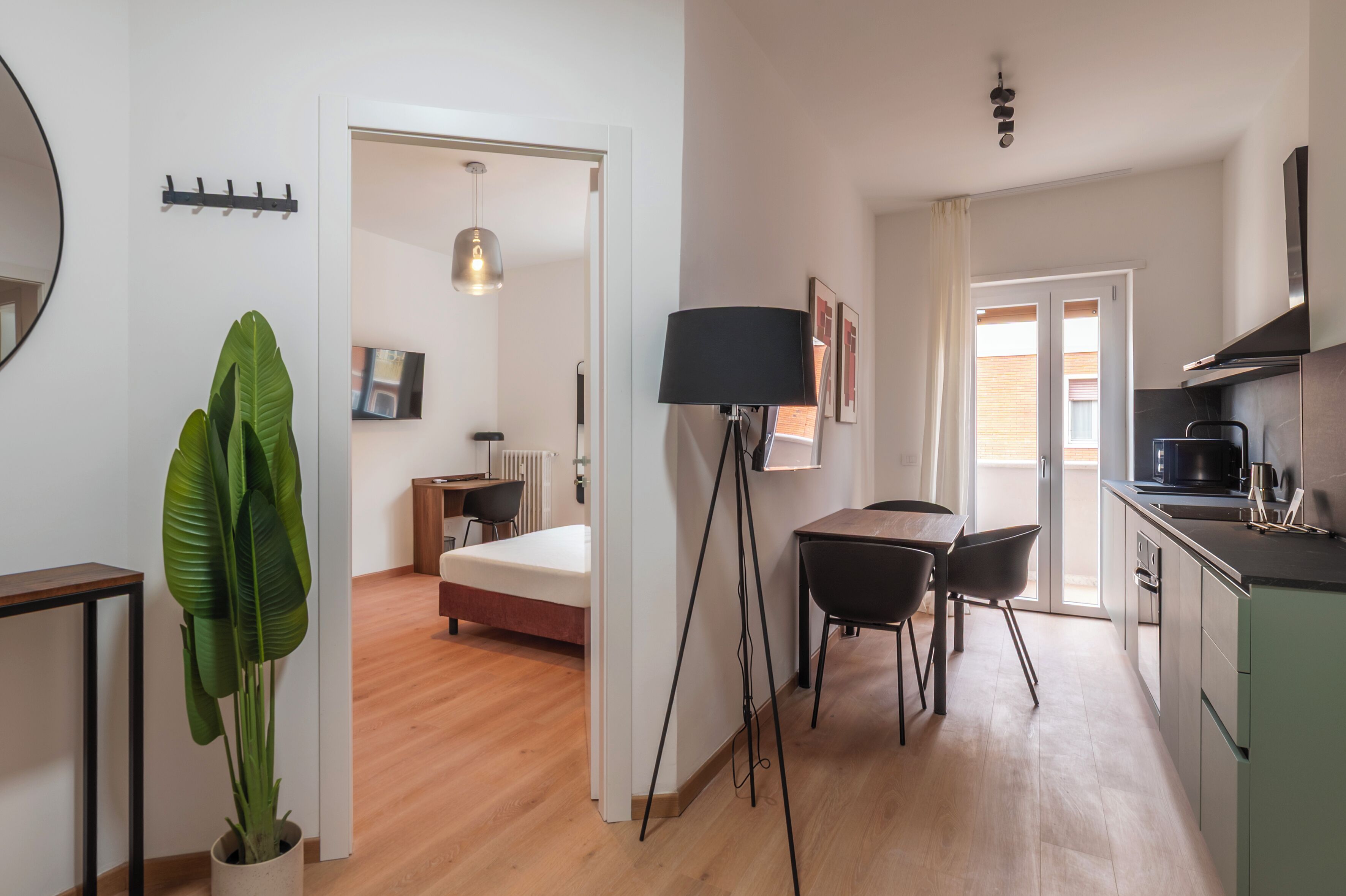 A modern apartment with a dining area, kitchen, and a bedroom with a bed and a radiator.