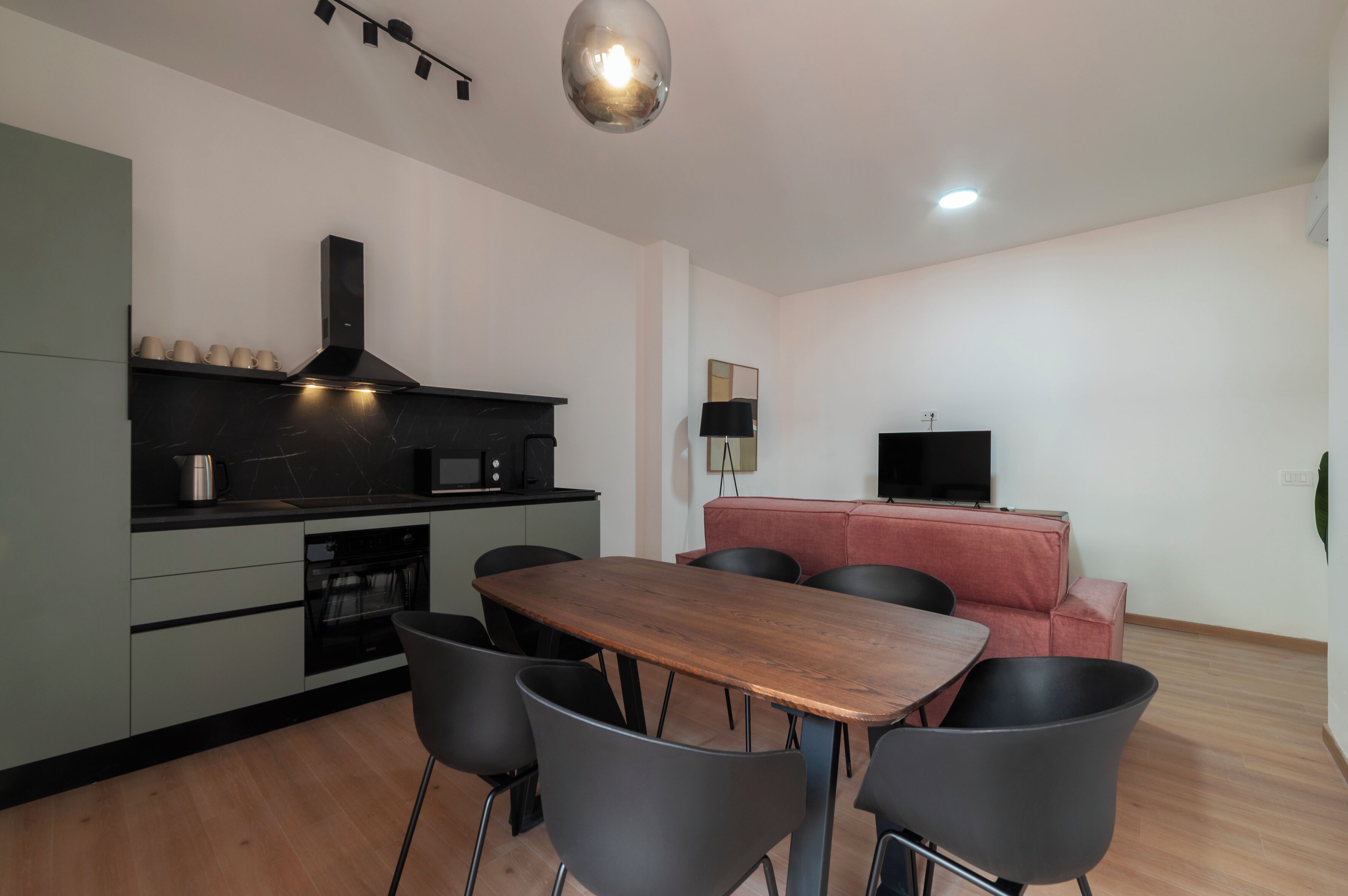 A modern kitchen with a dining area, including a wooden table and black chairs.
