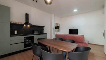 A modern kitchen with a dining area, including a wooden table and black chairs.