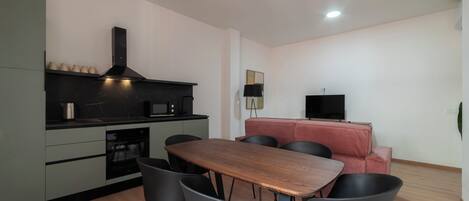 A modern kitchen with a dining area, including a wooden table and black chairs.