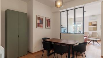 Un'area pranzo moderna con un tavolo in legno, sedie nere, un'armadiatura verde e arte astratta alle pareti.