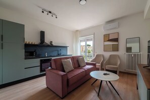 Ein modernes Wohnzimmer mit Sofa, Couchtisch und Küchenbereich mit Herd und Schränken.