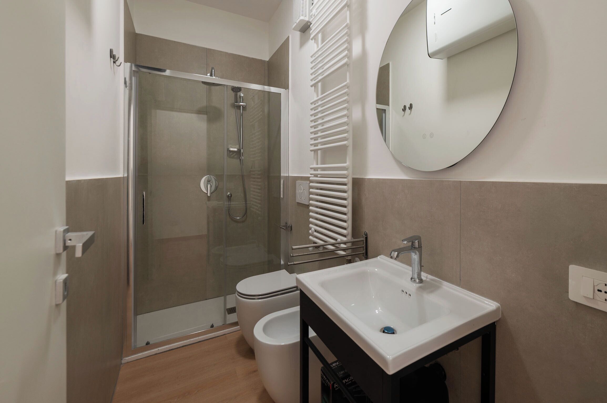 A modern bathroom with a glass-enclosed shower, a toilet, and a white sink.