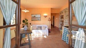 A cozy living room with a sofa, a table with a vase, a painting on the wall, and a stone wall. - Gorgeous home in Fabro (Fabro)