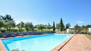 A rectangular swimming pool with a stone wall and lounge chairs along one side. - Gorgeous home in Fabro (Fabro)