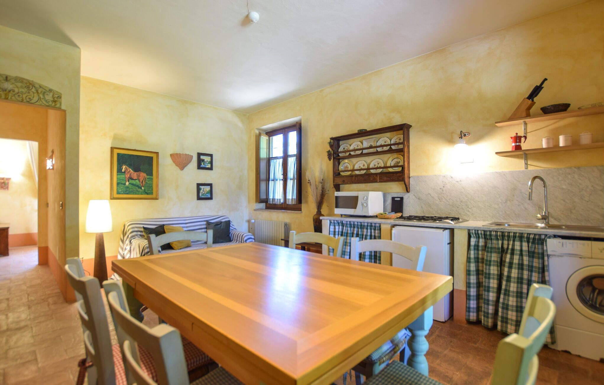 Una cocina acogedora con una mesa de madera, sillas, microondas, estufa y lavadora.