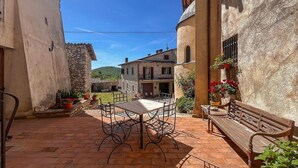 A courtyard with a table and chairs, a bench, and potted plants. - Amazing apartment in Frazione Montebibico (Frazione Montebibico)
