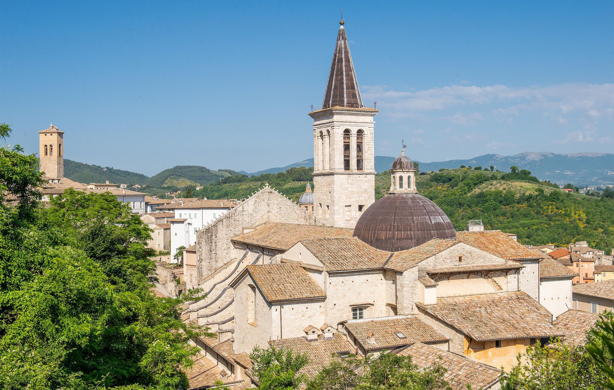 A historic town with stone buildings, a prominent church with a dome, and a bell tower.