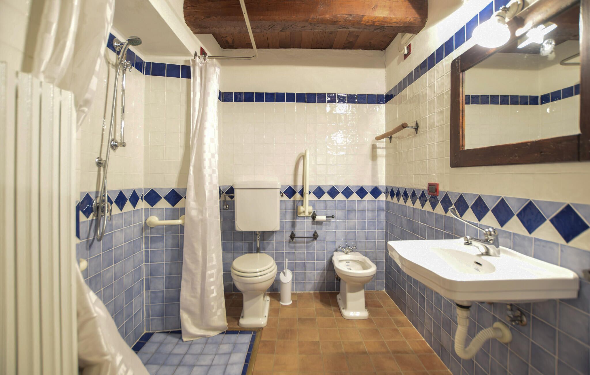 A bathroom with a shower, toilet, bidet, and sink.