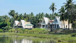 A resort with modern architecture, a body of water, and palm trees. - Rio Vista (Razole)