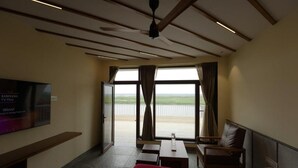 A hotel room with a bed, a TV, a desk, a chair, and a view of the outdoors. - Rio Vista (Razole)
