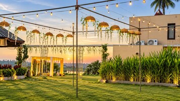 Un espacio al aire libre con una pérgola, luces colgantes y plantas suspendidas.