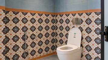 A bathroom with a patterned tile wall, a toilet, and a light fixture.