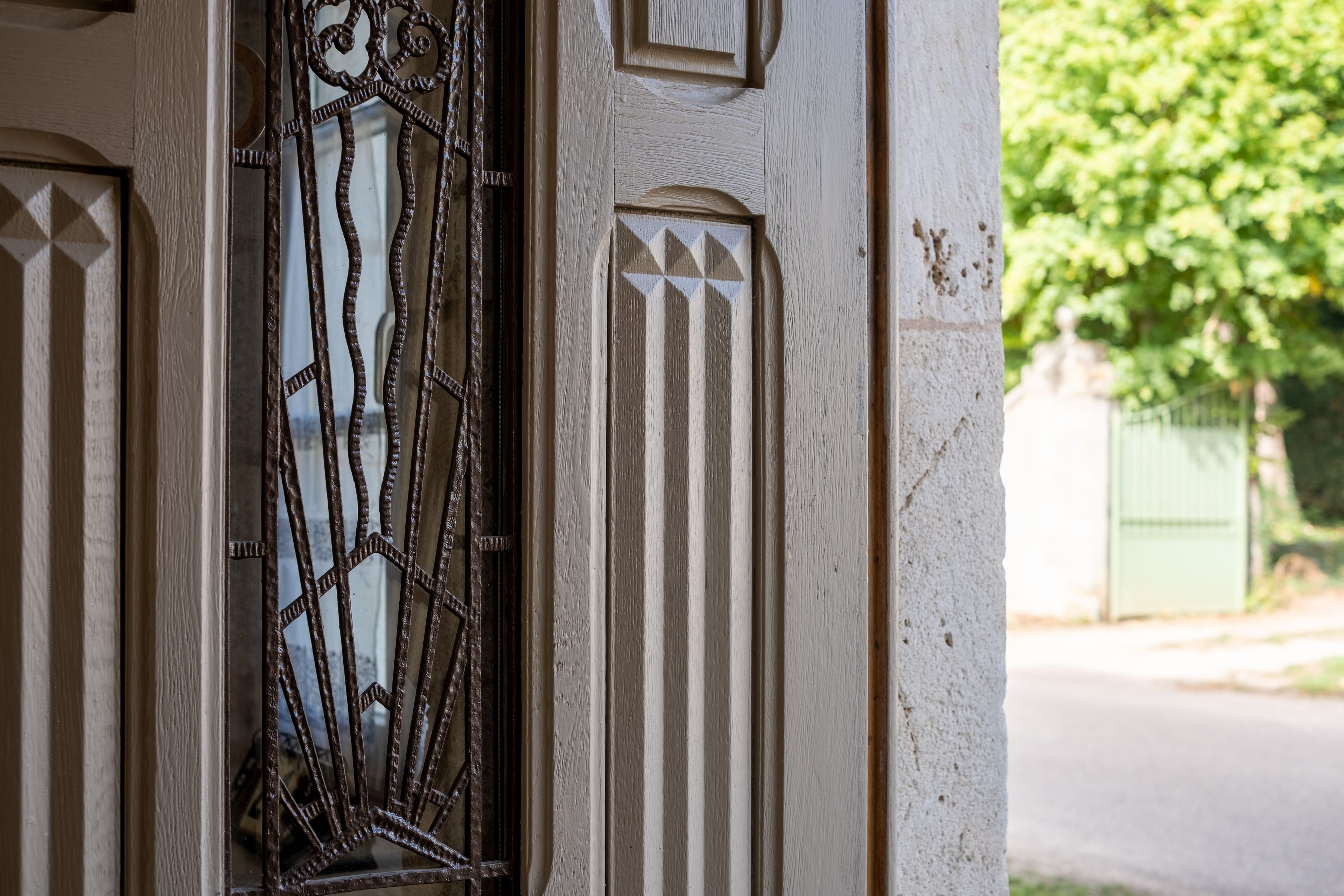 Un gros plan d’une porte ornée de motifs métalliques et d’une fenêtre à motifs géométriques.