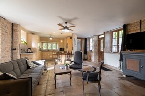 A spacious living area with a sofa, chairs, a coffee table, and a television.
