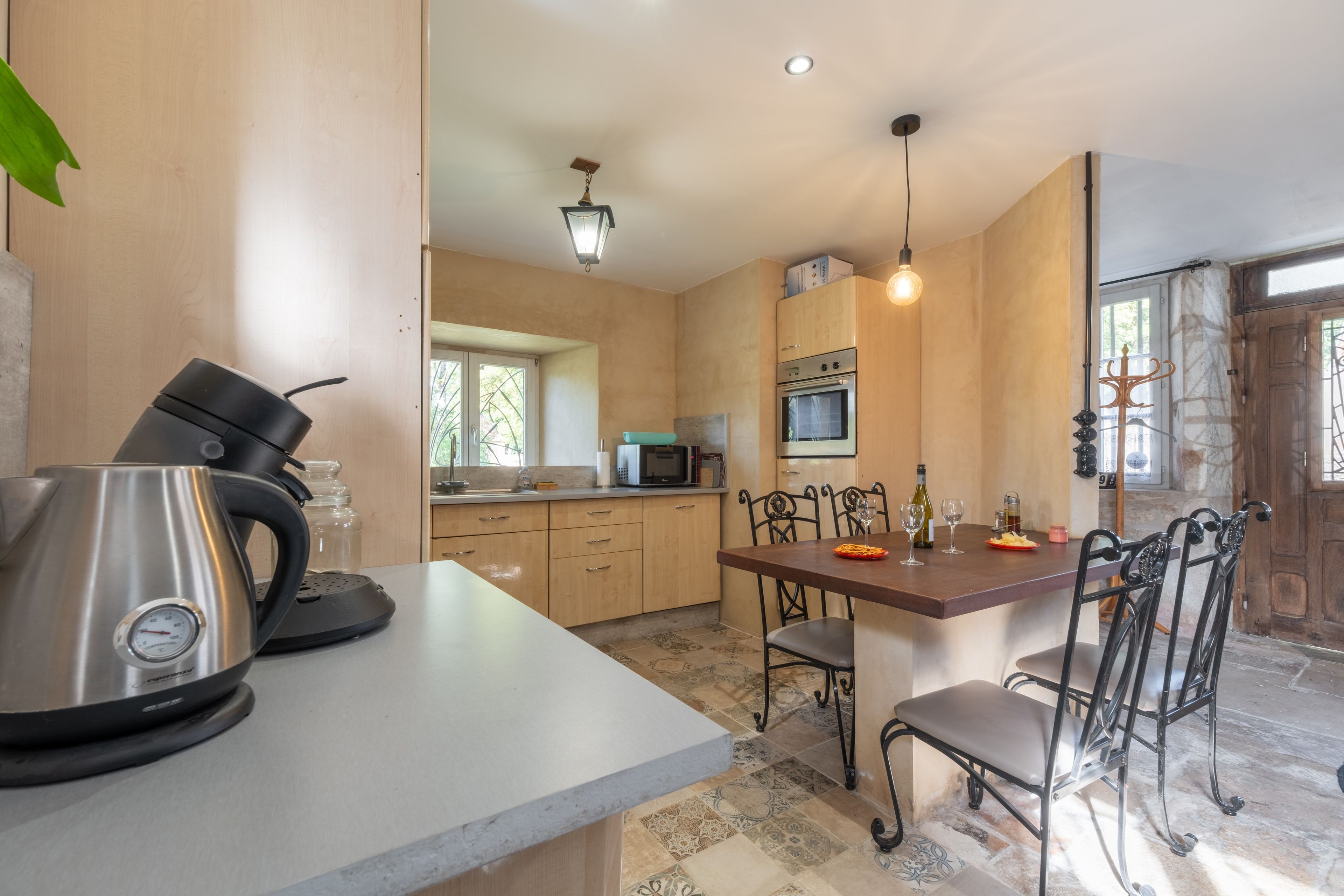 A modern kitchen with a kettle, microwave, and dining table with chairs.