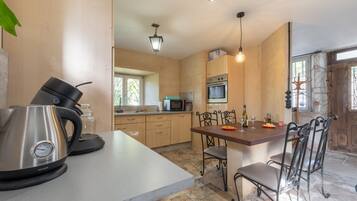 A modern kitchen with a kettle, microwave, and dining table with chairs.